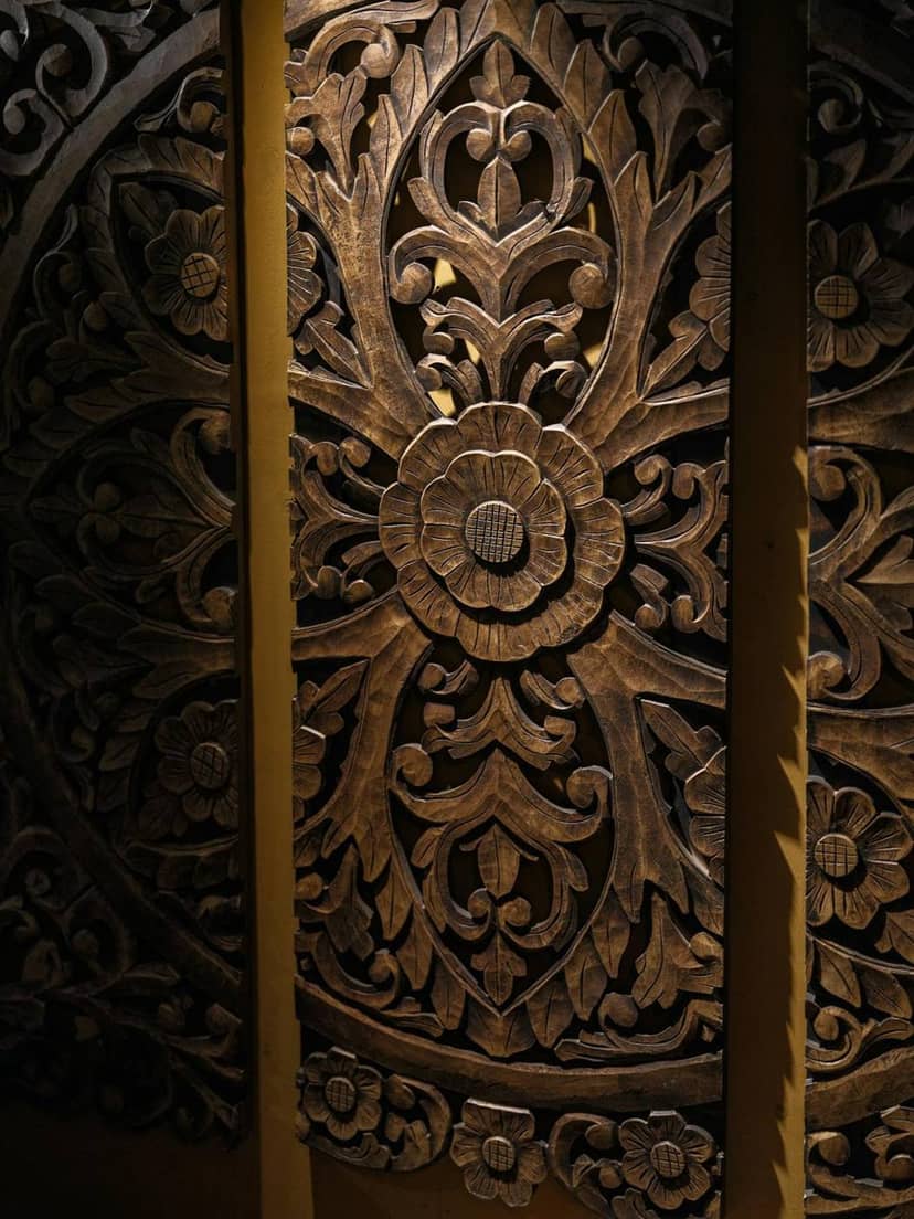 A dark wooden door with deep floral carving