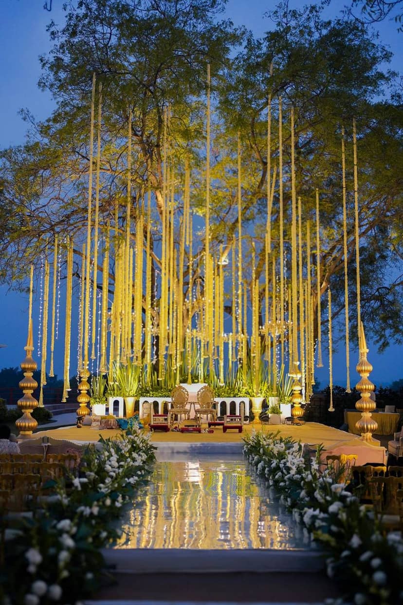 A golden mehndi stage under a tree at dusk